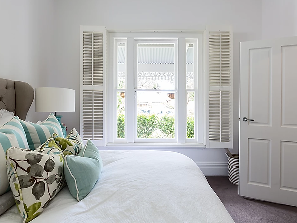 Bright interior with white plantation shutters and a panelled door in a sprayed finish